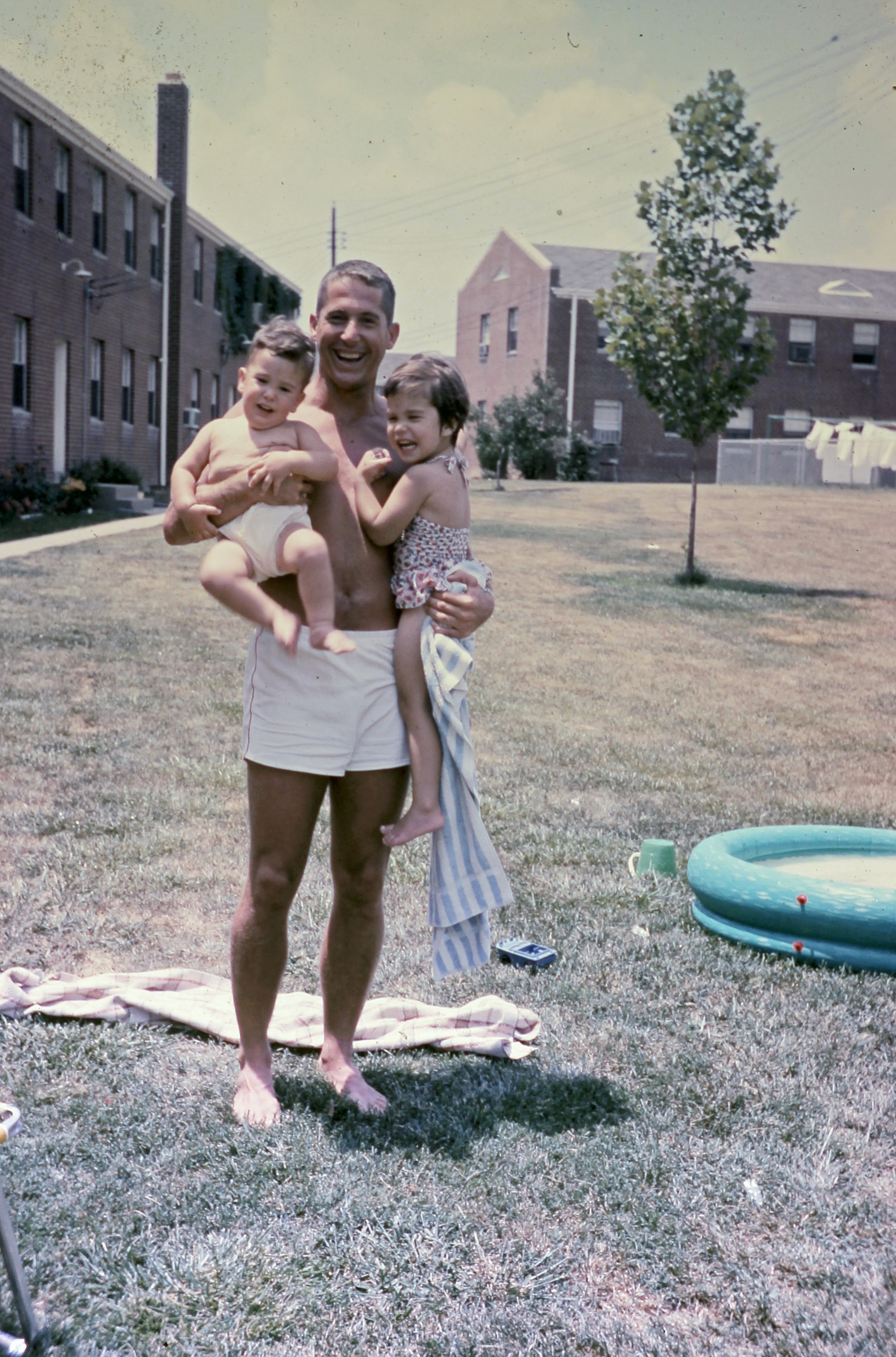 A young Don McCool holding two of his children in the backyard.